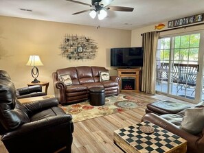 A living room with a fireplace, leather sofas, a television, and a large window. - Lakefront 3BR condo at Table Rock Lake with pool, patio, and WiFi. (Hollister)