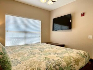 A bedroom with a bed, a television on the wall, and a window with blinds. - Lakefront 3BR condo with resort pool, balcony, and Table Rock Lake views. (Hollister)
