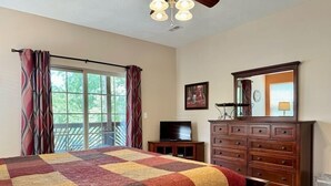 A bedroom with a large bed, a dresser, a television, and a balcony with curtains. - Lakefront 3BR condo with resort pool, balcony, and Table Rock Lake views. (Hollister)
