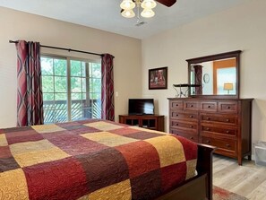 A bedroom with a large bed, a dresser, a television, and a balcony with curtains. - Lakefront 3BR condo with resort pool, balcony, and Table Rock Lake views. (Hollister)