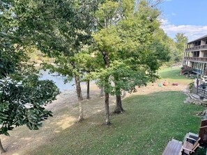 A grassy area with trees and a building in the background. - Lakefront 3BR condo with resort pool, balcony, and Table Rock Lake views. (Hollister)