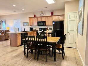 A kitchen with wooden cabinets, a dining table with chairs, a refrigerator, and a microwave. - Lakefront 3BR condo with resort pool, balcony, and Table Rock Lake views. (Hollister)
