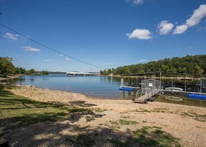 A calm lake with a dock and boats, surrounded by greenery and a clear sky. - Lakefront 3BR condo with resort pool, balcony, and Table Rock Lake views. (Hollister)
