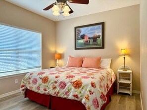 A bedroom with a bed, two bedside lamps, a ceiling fan, a window with blinds, and a framed picture on the wall. - Lakefront 3BR condo with resort pool, balcony, and Table Rock Lake views. (Hollister)