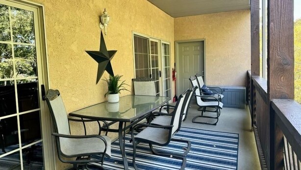 A covered patio with a glass table and chairs, a star decoration, and a potted plant. - Lakefront 3BR condo at Table Rock Lake with pool, patio, and Wi-Fi. (Hollister)