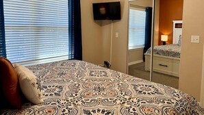 A bedroom with a bed, a television mounted on the wall, and a mirror reflecting the room. - Lakefront 3BR condo at Table Rock Lake with pool, patio, and Wi-Fi. (Hollister)