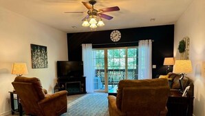 A living room with two brown armchairs, a television, a ceiling fan, and a large window with curtains. - Lakefront 3BR condo at Table Rock Lake with pool, patio, and Wi-Fi. (Hollister)
