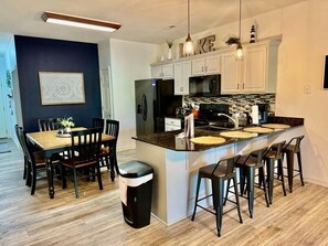 A modern kitchen with a central island, bar stools, and a dining table with chairs. - Lakefront 3BR condo at Table Rock Lake with pool, patio, and Wi-Fi. (Hollister)