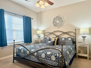 A bedroom with a bed, two bedside tables, a window with curtains, and a decorative wall piece. - Lakefront 3BR condo with resort pool, balcony, and 2 baths. (Hollister)