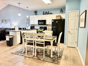 A kitchen with white cabinets, a black refrigerator, and a dining area with a table and chairs. - Lakefront 3BR condo with resort pool, balcony, and 2 baths. (Hollister)