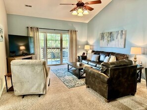 A living room with a sofa, armchair, and a flat-screen TV. - Lakefront 3BR condo with resort pool, balcony, and 2 baths. (Hollister)