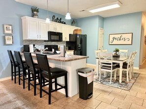 A kitchen with white cabinets, a black refrigerator, and a dining area with a table and chairs. - Lakefront 3BR condo with resort pool, balcony, and 2 baths. (Hollister)