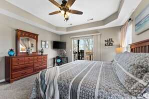Ein Schlafzimmer mit Bett, Kommode, Fernseher und Deckenventilator.