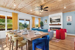 Un coin repas avec une table en bois dressée pour quatre personnes, un canapé et une cheminée.