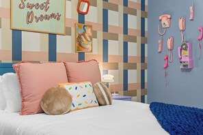 Una camera da letto con un letto, cuscini, una sveglia a parete e un telefono fissato al muro.