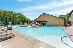 Une piscine avec un toboggan, des chaises longues et un espace de repos couvert.