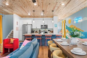 Une cuisine moderne avec des armoires blanches, des appareils en acier inoxydable et un plafond en bois.