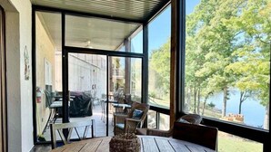 A wooden table with a woven basket centerpiece, large windows, and a view of a building and trees. - Lakefront 3BR condo at Table Rock Lake with pool, patio, and resort perks. (Hollister)