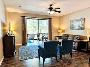 A living room with a ceiling fan, a sofa, a coffee table, and a dining area with chairs. - Lakefront 3BR condo at Table Rock Lake with pool, patio, and resort perks. (Hollister)