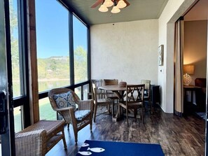 Ein Zimmer mit Esstisch und Stühlen, großen Fenstern und Blick ins Freie.