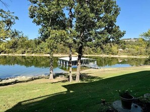 A lakeside property with a dock, a grassy area, and a building with a glass facade. - Lakefront 3BR condo at Table Rock Lake with pool, patio, and resort perks. (Hollister)
