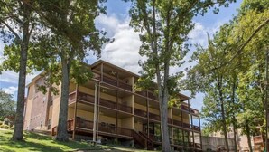 A multi-story building with balconies, surrounded by trees and a grassy area. - Lakefront 3BR condo at Table Rock Lake with pool, patio, and resort perks. (Hollister)