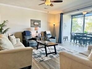Un salon spacieux comprenant un canapé, deux fauteuils, une table basse et un coin repas avec une table et des chaises.
