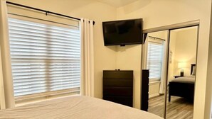 A bedroom with a bed, a television mounted on the wall, and a mirror. - Lakefront 3BR condo at Table Rock Lake with resort pool and balcony. (Hollister)