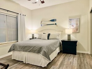 A bedroom with a bed, bedside tables, a headboard, a window with blinds, and a wall-mounted artwork. - Lakefront 3BR condo at Table Rock Lake with resort pool and balcony. (Hollister)