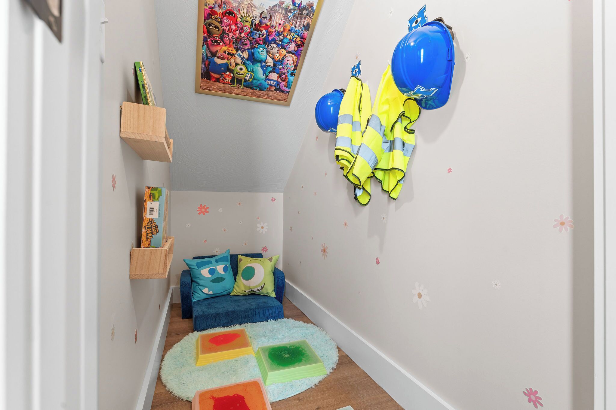 Una stanza giochi per bambini con un poster colorato, un casco blu e un divano blu con cuscini giocosi.