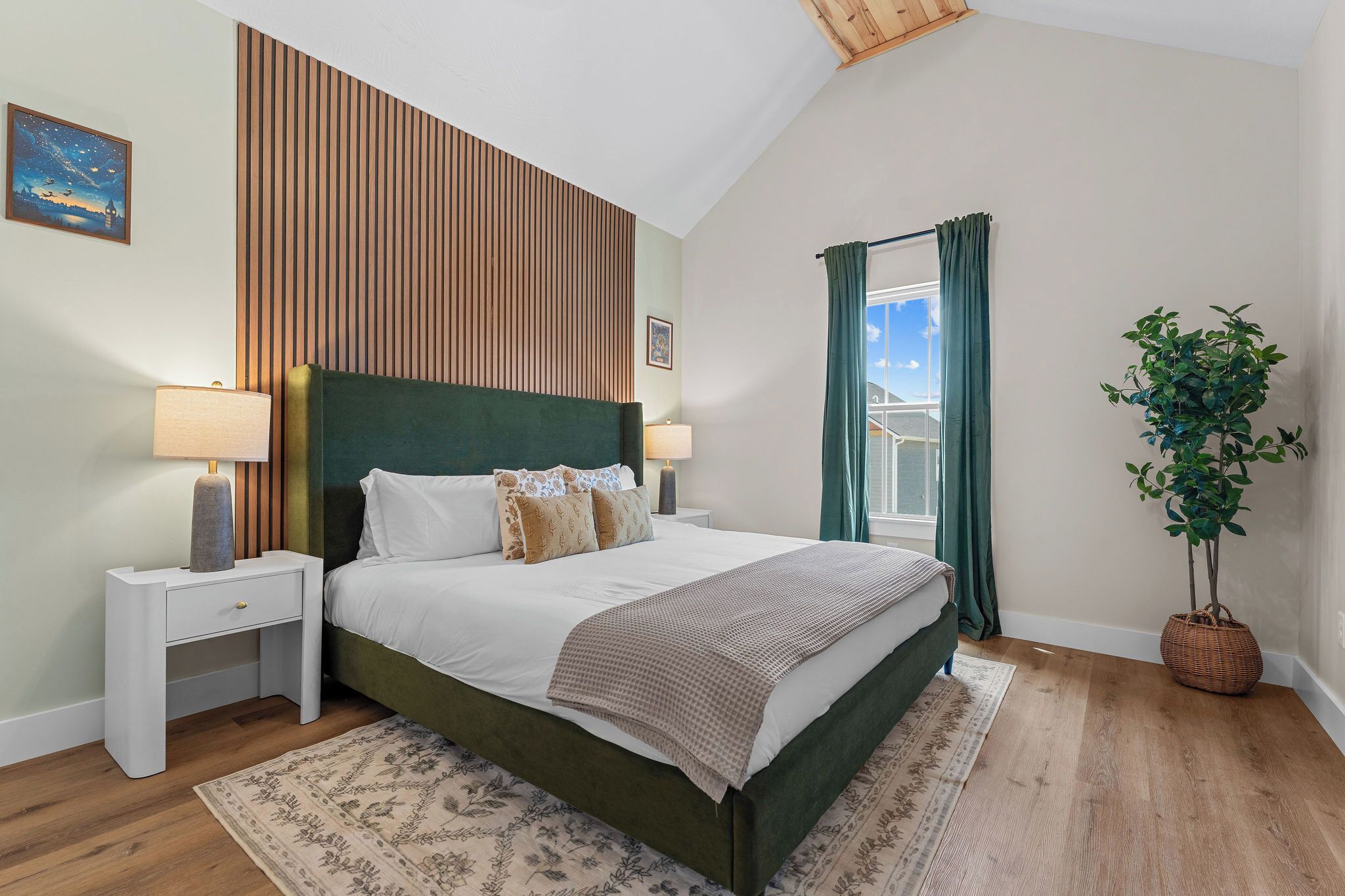 A bedroom with a bed, nightstands, a window with curtains, a plant, and a wall with vertical wooden slats.