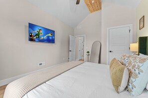 Quarto com cama, televisão na parede e porta.