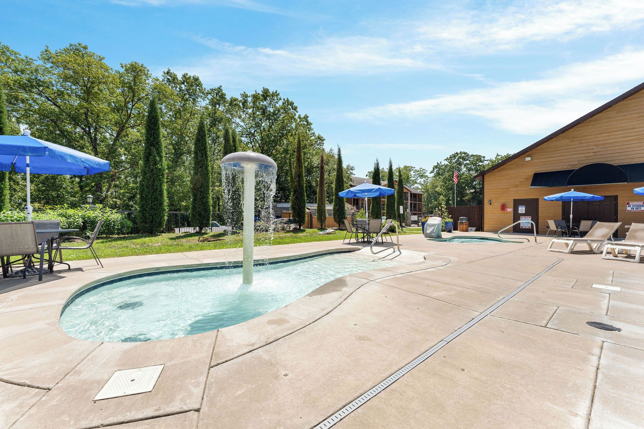 Ein Poolbereich mit Springbrunnen, Liegestühlen und Sonnenschirmen.