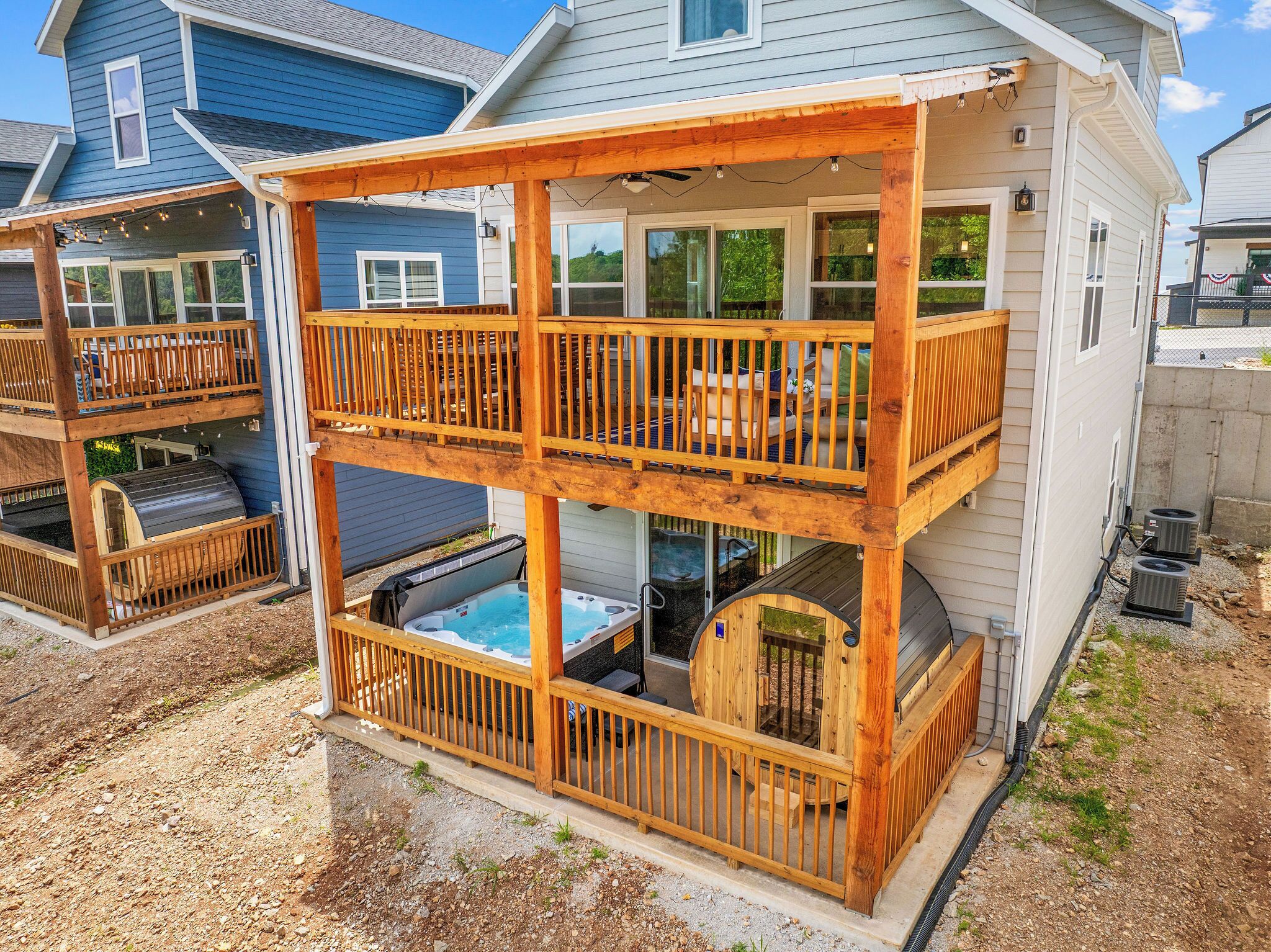 A two-story wooden deck with a hot tub and outdoor seating.