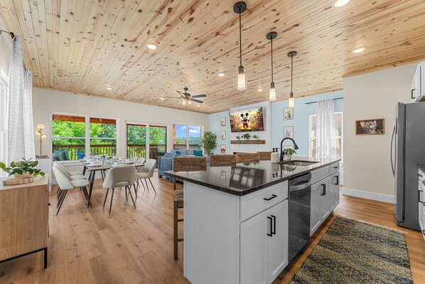 Una cocina amplia con una isla grande, techo de madera y un comedor con vista al exterior.