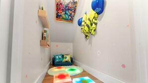 A narrow hallway with a blue sofa, a painting, and a blue balloon decoration. - NEW Disney Lodge 4 min SDC+Hot tub • Sauna • Slide (Branson)