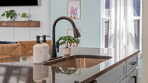 A modern kitchen with a stainless steel sink, a black faucet, and a potted plant on the counter. - NEW Disney Lodge 4 min SDC+Hot tub • Sauna • Slide (Branson)