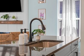 A modern kitchen with a stainless steel sink, a black faucet, and a potted plant on the counter. - NEW Disney Lodge 4 min SDC+Hot tub • Sauna • Slide (Branson)