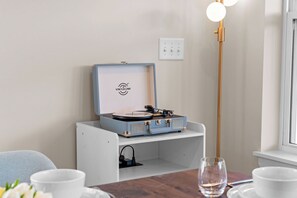 Um quarto com toca-discos numa prateleira branca, uma tomada e um abajur de chão alto.
