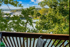 A view from a balcony overlooking a lake with boats, surrounded by trees. - 3BR lakefront condo with balcony, pool, and resort access (Hollister)