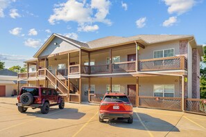 A two-story building with a balcony on the second floor, a covered parking area, and a red vehicle parked in front. - 3BR lakefront condo with balcony, pool, and resort access (Hollister)