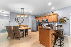 A modern kitchen with wooden cabinets, stainless steel appliances, and a central island with bar stools. - 3BR lakefront condo with balcony, pool, and resort access (Hollister)