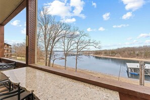 Una habitación con vista a un lago, un comedor con mesa y sillas, y un ventanal con vistas al paisaje.
