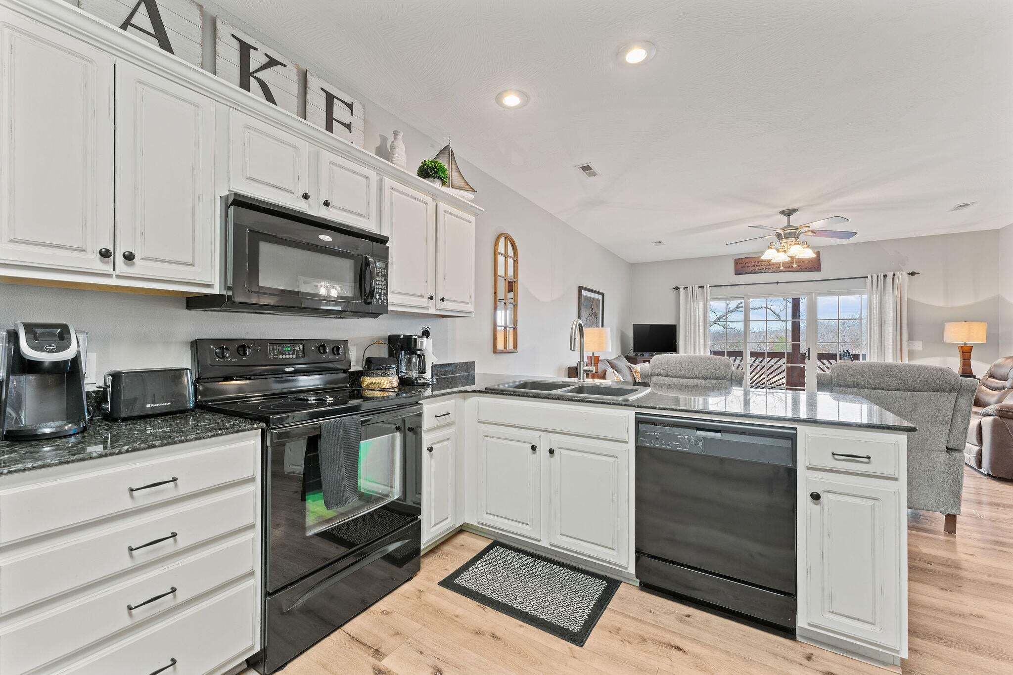 A modern kitchen with white cabinetry, a black microwave, and a dishwasher.