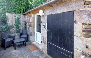 A stone building with a black door, a white door, and a small window. There are two wicker chairs and a bench outside. - Lovely home in Henanbihen with WiFi (Henanbihen)