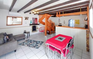 A room with a fireplace, a sofa, a dining table with chairs, a kitchen area, and a staircase. - Lovely home in Henanbihen with WiFi (Henanbihen)