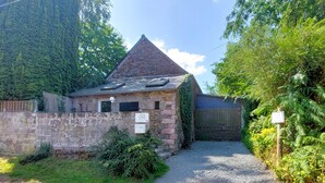 A stone building with a triangular roof, a gravel driveway, and a wooden fence. - Lovely home in Henanbihen with WiFi (Henanbihen)