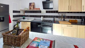 A modern kitchen with a gas stove, oven, and dishwasher. There is a wicker basket with bottles and a red folder on the counter. - Lovely home in Henanbihen with WiFi (Henanbihen)