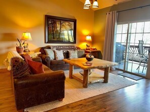 A living room with a sofa, a coffee table, and a painting on the wall. - Lakefront 3BR condo with pool, balcony, fireplace, and resort views. (Hollister)