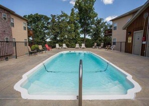 A rectangular swimming pool with a metal safety railing, surrounded by lounge chairs and a paved deck. - Lakefront 3BR condo with pool, balcony, fireplace, and resort views. (Hollister)
